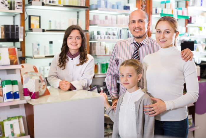 Cheerful smiling family of three happy persons getting help of a pharmacist in the pharmacy