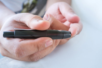 man pricking his finger to draw a drop for blood testing